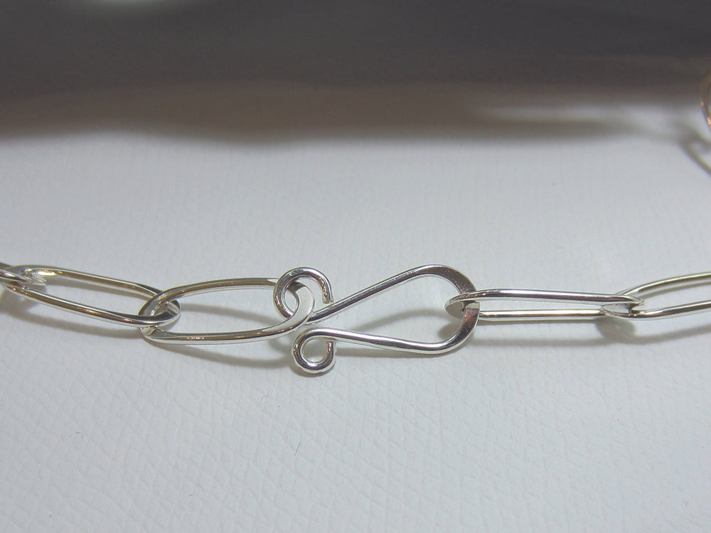 A nice flat link, sterling silver necklace which is 24" or 60cm long. Each link is 2cm long and the easy to use hook clasp can be attached to any link allowing the necklace to be worn at different lengths. The necklace weighs 19.5 grams and so carries a full set of Hallmarks. 925 Canterbury