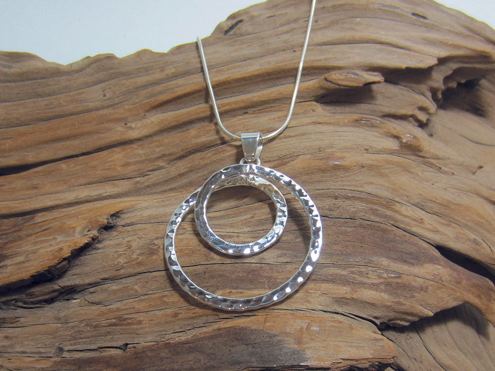 A bold hammered, sterling silver spiral pendant which measures 36mm across. It is shown here on a fine snake chain. 925 Canterbury