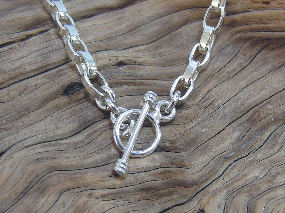 Stylish, sterling silver squared-off belcher chain bracelet with a t-bar fastener. It is 7.5" long and weighs around 13 grams. It is stamped with a full set of UK Hallmarks. 925 Silver Canterbury