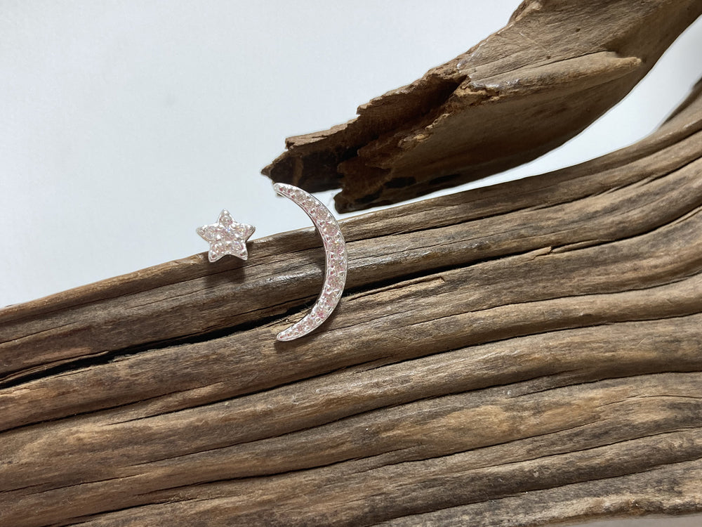 Mismatched cubic zirconia studs which look equally as good worn one in each ear or together in one lobe. The crescent moon is 15mm long and the star is 5mm across. Sterling silver, 925 Canterbury